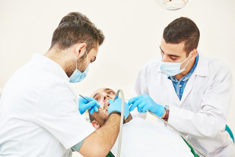Zwei Zahnärzte behandeln einen Patienten gleichzeitig